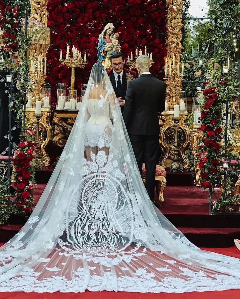 Kourtney Kardashian stands at her wedding altar wearing a cathedral-length veil embroidered with the Virgin Mary.