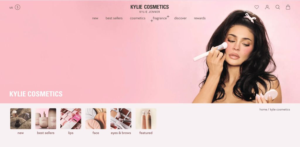 Kylie Cosmetics website featuring Kylie Jenner applying makeup against a pink background, with product categories displayed below.